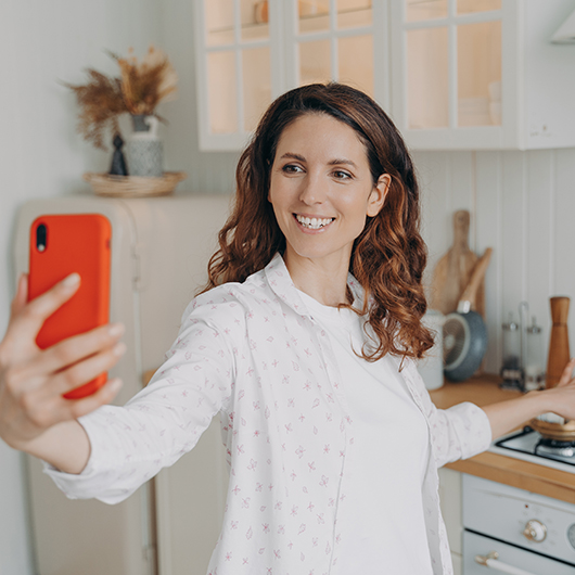 A women in white clothes is taking a selfie in her kitchen